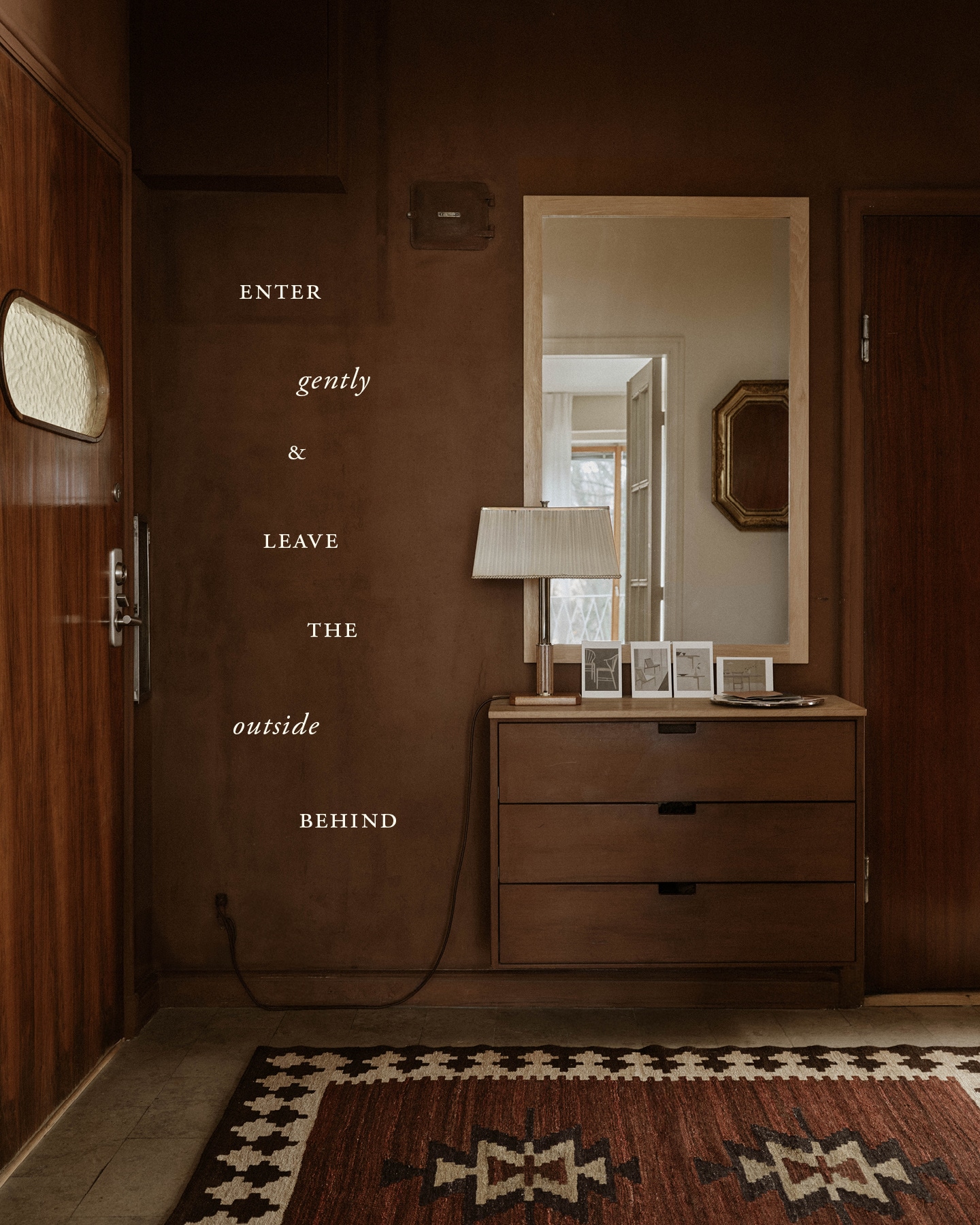 chest of drawers and mirror in a hallway with brown walls and the logo ‘Enter gently and leave the outside behind’