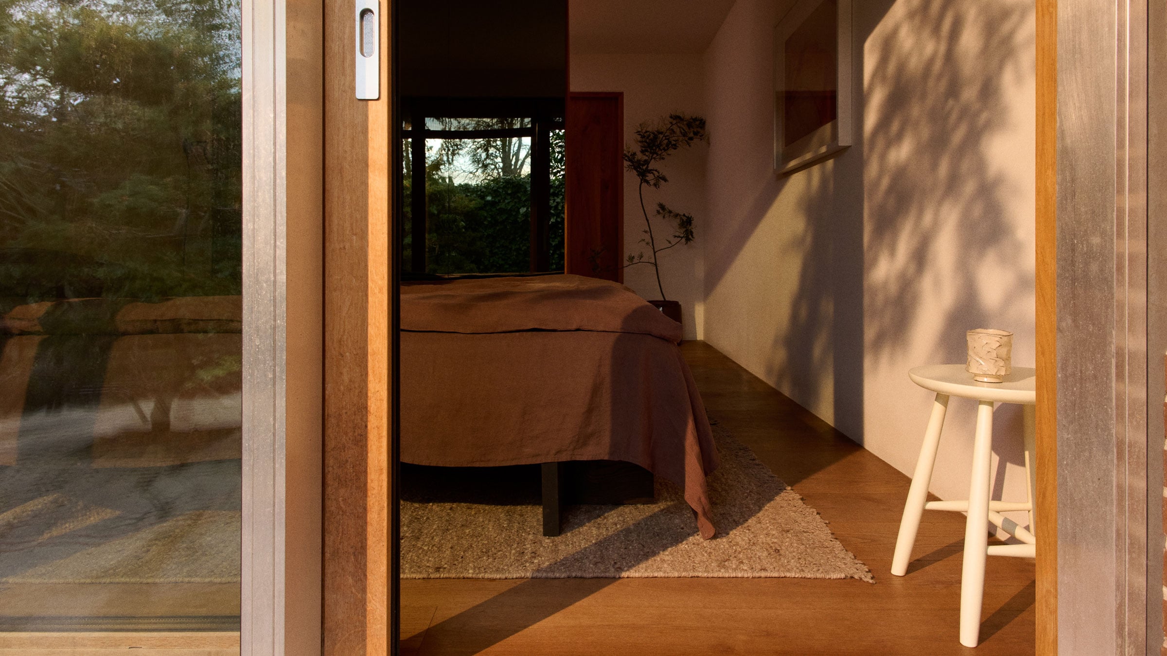 bedroom with a rug under the bed dressed in earthy brown linens