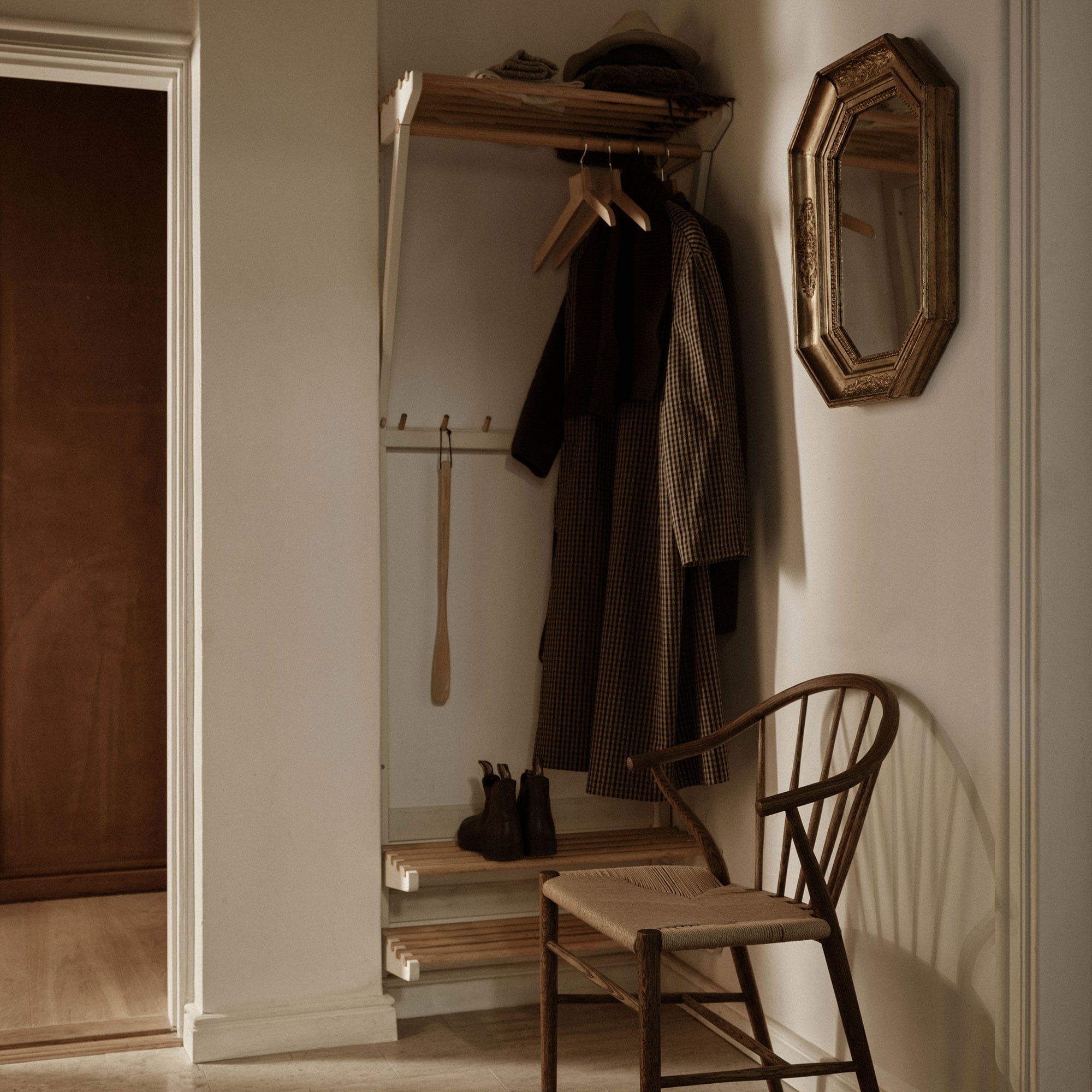 Hat and shoe rack in a hallway with an armchair next to it